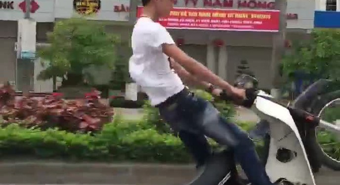 Nam thanh niên chạy xe máy một bánh trên phố.